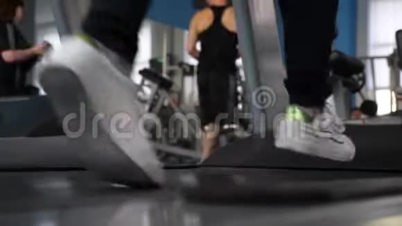 加强腿部肌肉跑穿运动鞋的女孩的腿在跑步机上特写在健身房散步心脏负荷女火车视频的预览图
