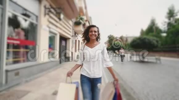 美丽的年轻女子购物后快乐地散步慢动作视频的预览图