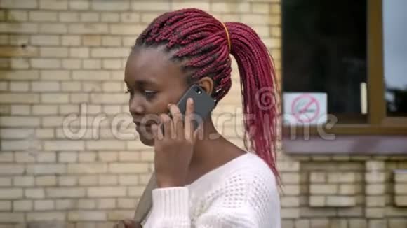 年轻的非洲美丽学生离开大学打电话女人带着粉红色的恐惧在公园散步视频的预览图