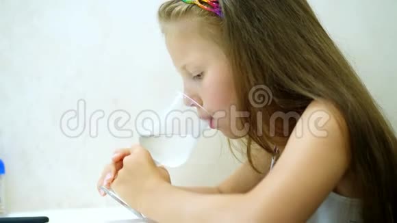 在餐馆里在桌子上那个小女孩喝着碳酸矿泉水杯子里有气泡肖像画视频的预览图