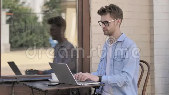 年轻人在笔记本电脑上庆祝成功坐在户外视频的预览图