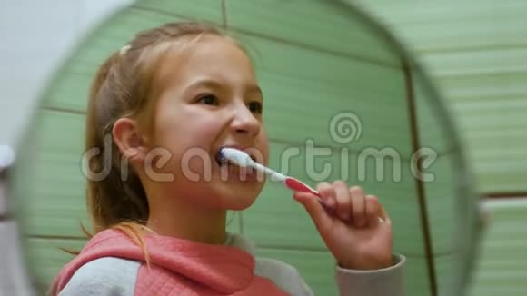 一个美丽的小女孩一头秀发在镜子里彻底地刷牙视频的预览图