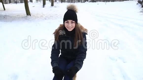 女孩在冬天的天气里坐在雪橇上男人帮他的女朋友滚她视频的预览图