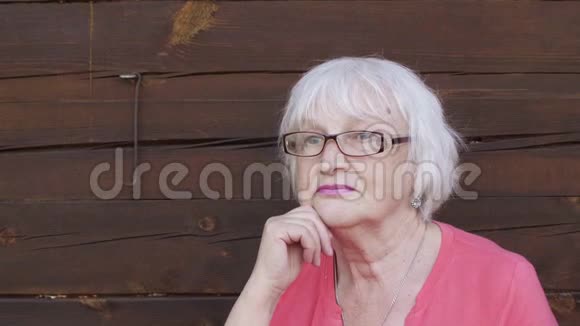 一位戴着灰色头发的眼镜的漂亮的老年妇女眺望户外视频的预览图