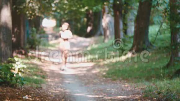 年轻的女士在跑步女跑步者跑过夏季公园路在公园里健身很漂亮的女孩视频的预览图