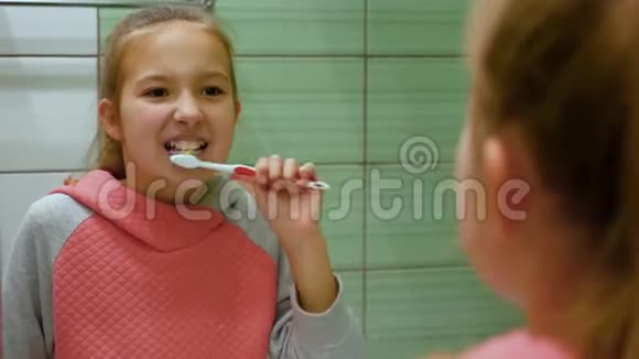 一个美丽的小女孩一头秀发在镜子里彻底地刷牙视频的预览图