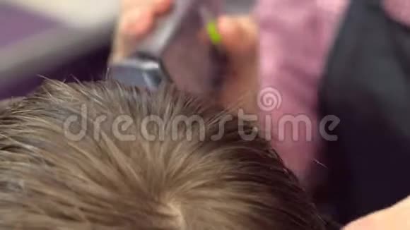 理发师在男孩的头上用剪刀剪头发俯视图造型师手特写视频的预览图