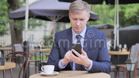 商务人士在户外咖啡厅使用智能手机视频的预览图
