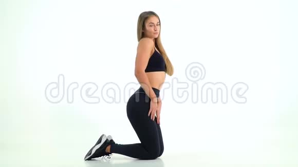 金发的运动女孩站在膝盖上摆姿势视频的预览图
