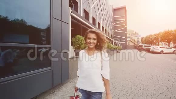 微笑的女人慢吞吞地拿着购物袋走在街上视频的预览图