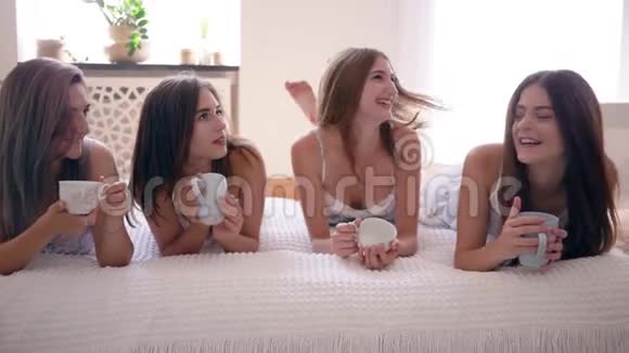 茶话会美丽的朋友女孩在床上和杯子一起谈笑风生视频的预览图