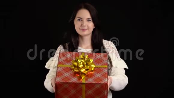 年轻女子在黑色背景上赠送礼品盒圣诞快乐带白色丝带的礼品盒视频的预览图