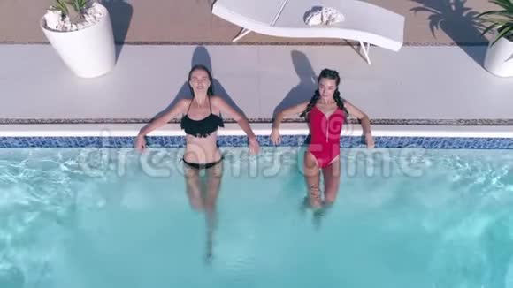 穿着泳衣的漂亮女朋友在夏季周末在蓝色泳池边休闲视频的预览图