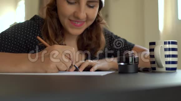用刻字技术在一张纸上写圣诞帽书法的年轻女子特写镜头她写字视频的预览图
