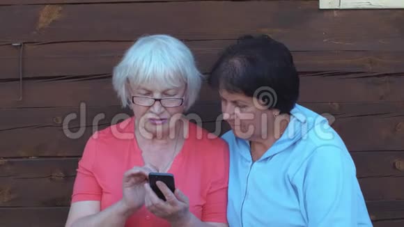 两位老妇人在农村看手机在户外聊天视频的预览图