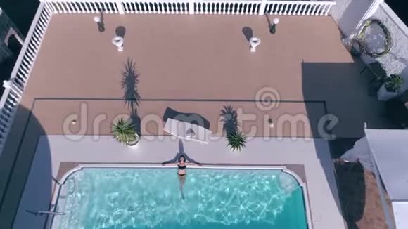 穿着泳衣的可爱女孩正躺在蓝色游泳池里度过昂贵的暑假视频的预览图