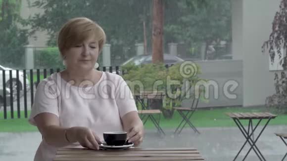 一位坐在露台上品尝茶的漂亮老妇人的特写镜头视频的预览图