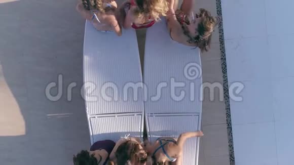 避暑胜地一群迷人的女孩穿上泳衣轮流躺在游泳池附近的躺椅上视频的预览图