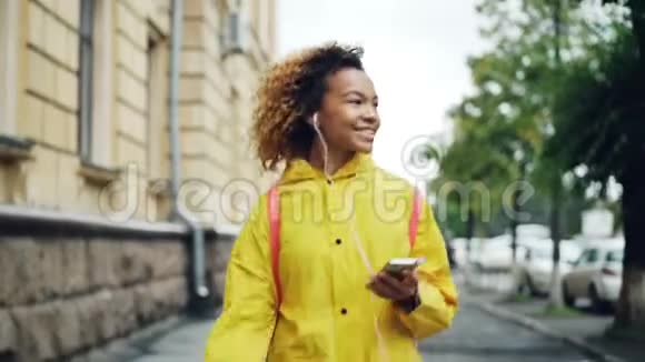 免费的非裔美国学生正在散步通过耳机听音乐闲暇时唱歌视频的预览图