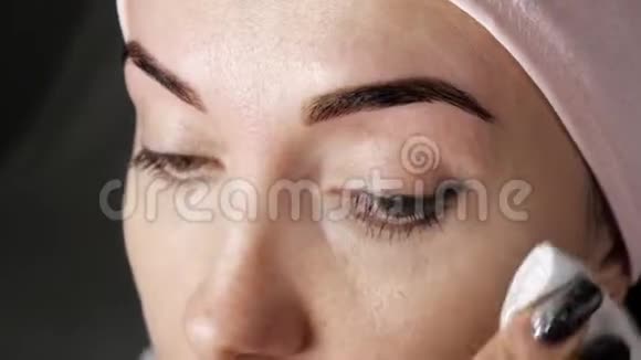 染眉毛女人用棉垫和乳液擦拭眉毛的特写视频的预览图