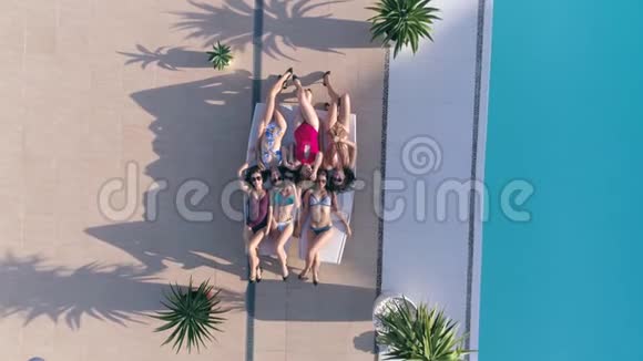 日光浴快乐的朋友女孩穿上泳装和太阳镜在豪华假日在泳池边的休息室放松视频的预览图