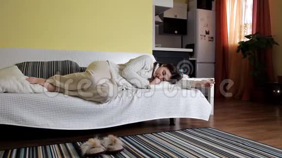 一个年轻的女孩穿着家服在沙发上睡着了睡觉后醒来视频的预览图