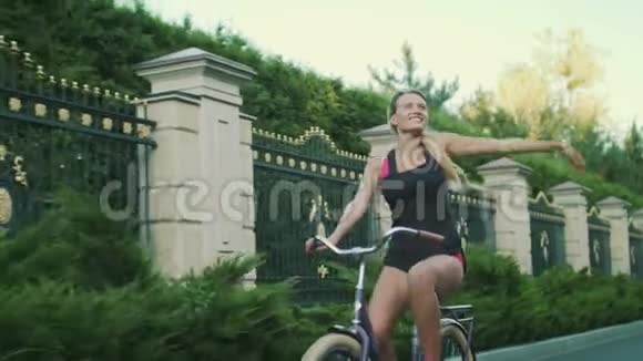 快乐的骑自行车的女人喜欢骑自行车在夏天的公园里举手视频的预览图