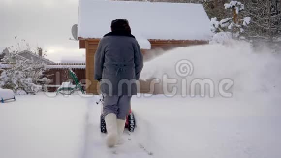 冬天男人用白雪皑皑的木屋背景来清洁雪视频的预览图