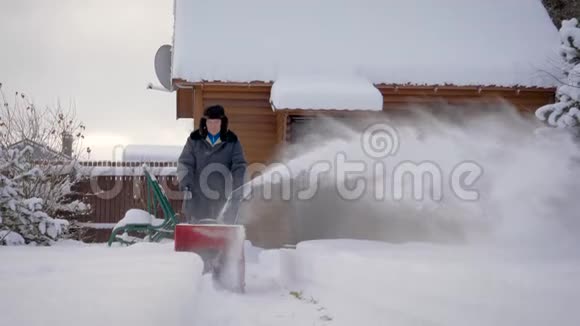 冬天男人用白雪皑皑的木屋背景来清洁雪视频的预览图