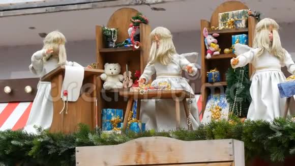 三个动人的天使娃娃正在孩子们的圣诞小亭的屋顶上用雪白衣服包装礼物视频的预览图