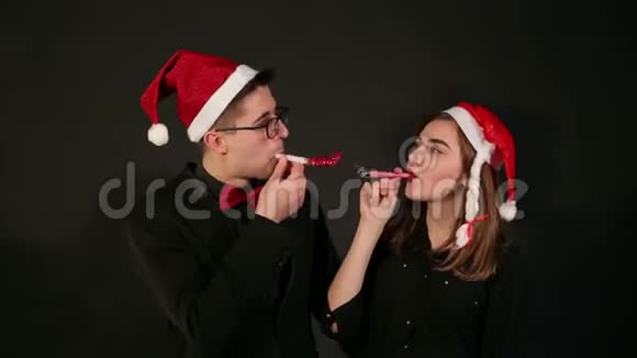 一对戴着圣诞帽的夫妇的肖像在新年里吹着口哨视频的预览图