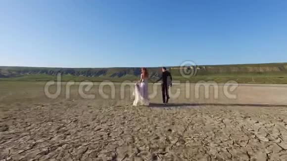 新娘和新郎在纹理地面上行走干盐湖视频的预览图