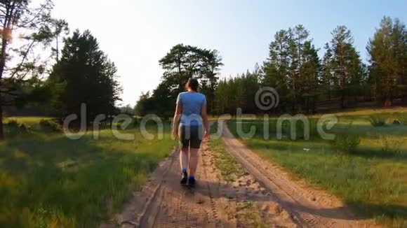 日落时分在乡间小路上散步的女孩视频的预览图