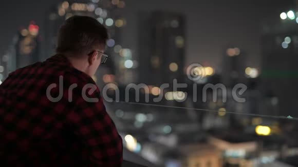 年轻英俊的嬉皮士看城市夜景视频的预览图