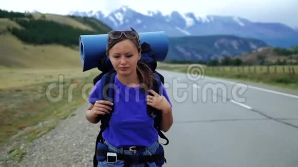 年轻的旅游妇女带着背包走在山路上环顾四周下雪了视频的预览图