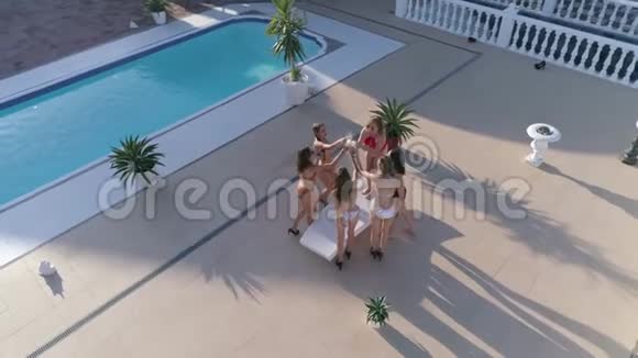 夏天在昂贵的节日里穿着泳衣的活泼活泼的女孩正在游泳池附近跳舞和喝酒视频的预览图