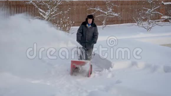 在冬天一个人从雪堆中清除院子里的积雪视频的预览图