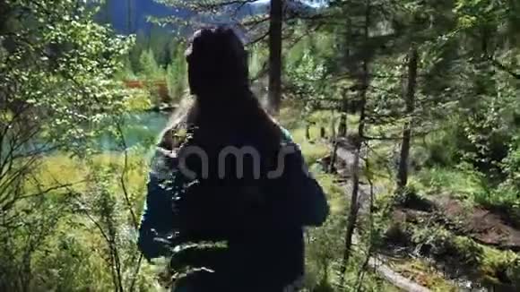 阳光明媚的一天年轻的女游客正在山上一个风景如画的蓝色湖泊上靠近背面视频的预览图