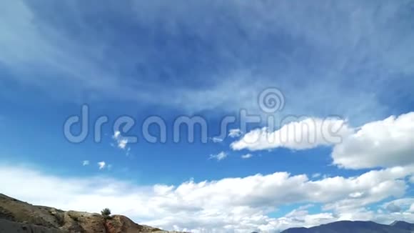 戴帽子的旅行女孩坐在一座红山的边缘背景中有风景和多云的天空视频的预览图