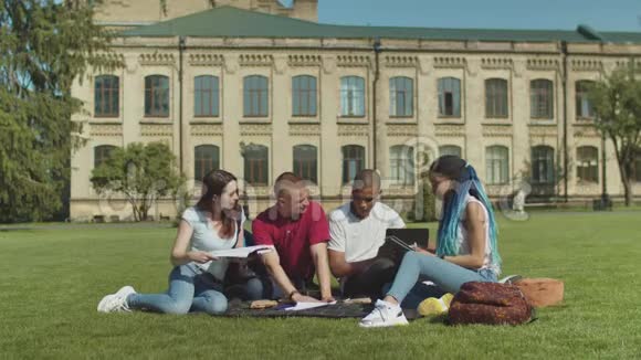 坐在绿色草坪上学习的大学生视频的预览图