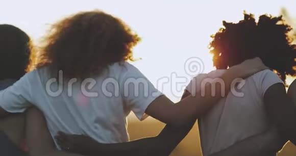 一个卷发非洲小伙子和她的朋友走下田惊人的天空灯光抱在一起慢慢慢慢视频的预览图