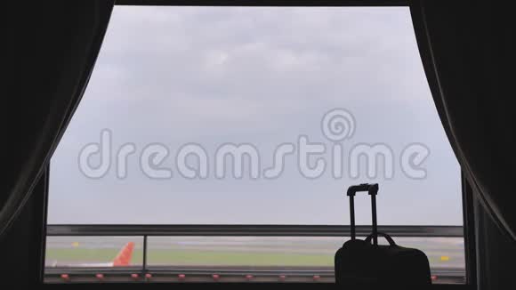 机场附近酒店的窗户和飞机起飞的背景是手提箱或行李视频的预览图