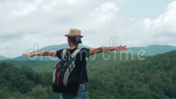 游客年轻女孩背着背包站在山顶欣赏山谷景色带着她快乐的徒步旅行者视频的预览图