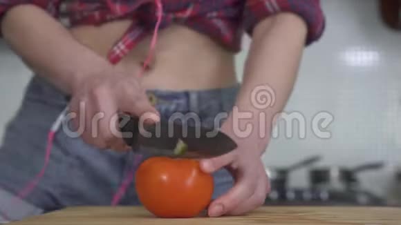 苗条的女孩赤着肚皮穿着别针穿上衣服跳舞在木板上切新鲜的西红柿关门视频的预览图