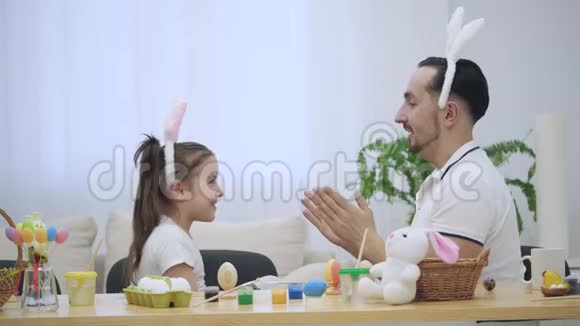 父亲正在教女儿玩游戏他们正在玩他们的手漂亮有趣幼稚的游戏视频的预览图