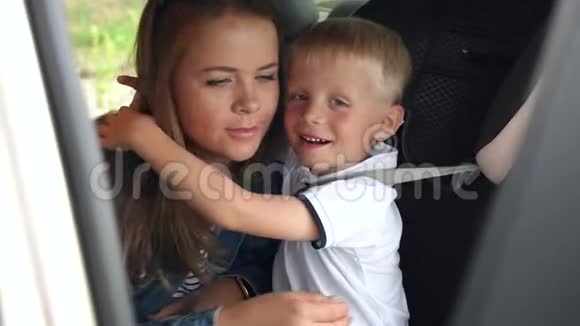 一个快乐的母亲和她的儿子在车上男孩在车座位上的肖像视频的预览图