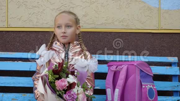 带着花在长凳上等第一课的学校女孩回到学校的概念视频的预览图