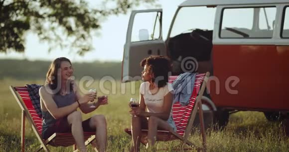 在一片美丽的田野里一对令人敬畏的种族夫妇和他们的复古面包车在野餐时玩得很开心视频的预览图