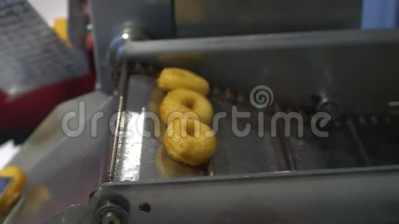 一个厨师使用专业的厨房钳子把甜甜圈煮在甜甜圈机器上并把它们放在一个盒子里给客户视频的预览图