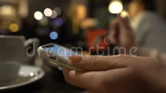 年轻女性喝咖啡在智能手机上看照片特写视频的预览图